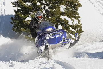 Fototapeta na wymiar snowmobile rider racing machine through mountain powder
