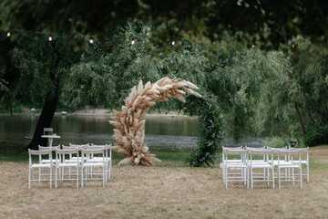 Wedding arch under the tree and chairs for guests. Outside ceremony place. Wedding arch. Wedding...