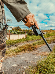 close-up of a human hand with a pistol, under a blue sky, against the background of a road going into the distance