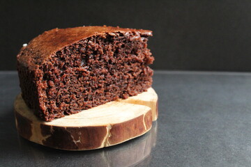 chocolate brownie pie on a wooden backing stand in a black place with copy space for text
