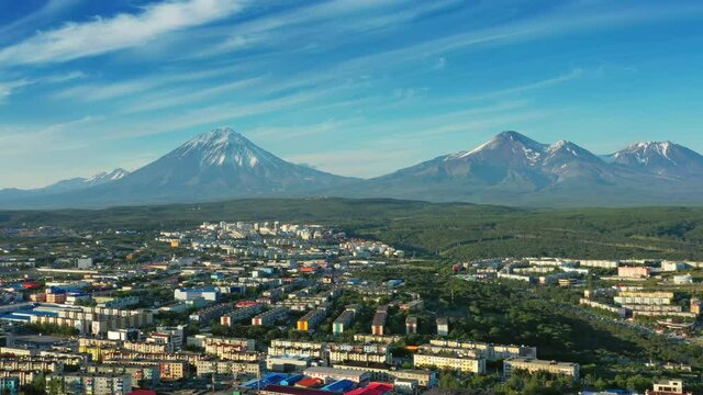 Flying over Petropavlovsk-Kamchatsky city at sunset and cone of volcano. Kamchatka Peninsula, Russia, 4k
