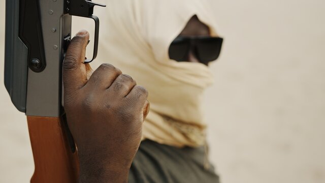 Black man with head covering in desert with AK-47 machine gun. High quality photo