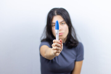 Young girl holds a positive pregnancy test in her hand. Unplanned pregnancy. Selective focus