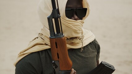 Black man with head covering in desert with AK-47 machine gun. High quality photo