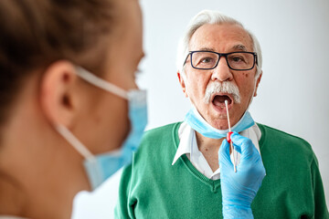 Female doctor specialist with face mask holding buccal cotton swab and test tube ready to collect DNA from the cells on the inside of a senior man patient
