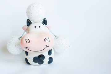 Black and white clay bull figurine decorated with Christmas decorations on a white background. New year of the bull