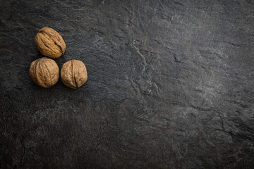 Drei getrocknete Walnüsse auf dunklem Schiefer Untergrund