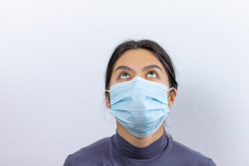 Girl in protective medical mask looking up on a white background