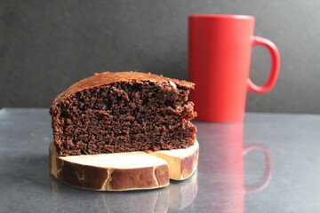 chocolate brownie pie on a wooden stand log cabin back in the background is a red mug a Cup of tea coffee milk on a black background with a copy space for the text Breakfast dessert cafe tea coffee