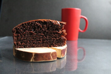 chocolate brownie pie on a wooden stand log cabin back in the background is a red mug a Cup of tea coffee milk on a black background with a copy space for the text Breakfast dessert cafe tea coffee