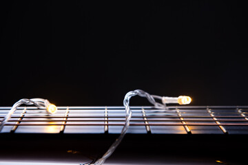 part of a guitar close-up wrapped in a garland on white. Concept on the theme: New Year's sale of musical instruments