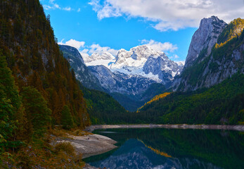 Fototapeta na wymiar Beautiful Gosausee lake landscape with Dachstein mountains, forest, clouds and reflections in the water in Austrian Alps