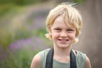 Little boy smiling in pretty location with camera strap visible around his neck