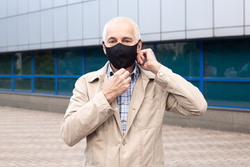 Portrait of senior businessman wearing medical mask in city near office buildings