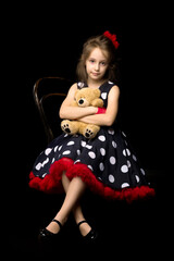 Cute girl in polka dot dress holds a teddy bear