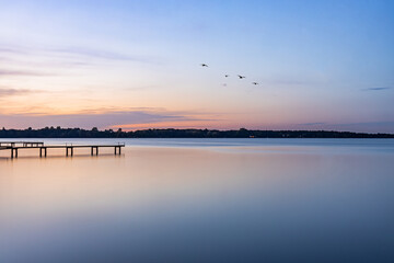 Fototapeta na wymiar sunset and birds over the lake, footbridge in the lake 