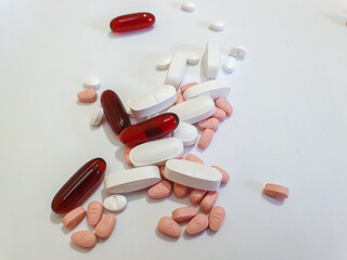 Different types of capsules and pills mixed together white background pink red and white pills