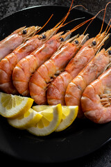 Boiled tiger prawns on black plate. Tasty shrimps.