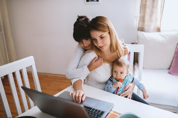 Mother with her baby boy and cute girl working from home