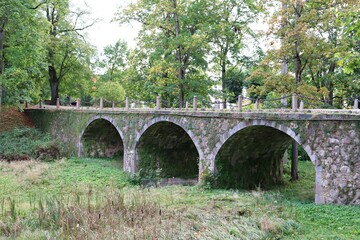 Fototapeta na wymiar Very old stone bridge in the park next to the Manor in the Latvian Kazdanga in October 2020