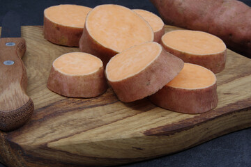 Organic sweet potatoes on a wooden cutting board. Healthy eating
