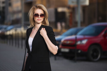 Obraz premium Young fashion blond business woman in black blazer and sunglasses