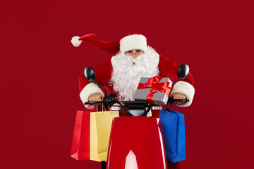 Portrait of a cheerful crazy Santa Claus on a retro motorcycle. Delivers gifts on a red studio background. Christmas and New Year gifts and sales