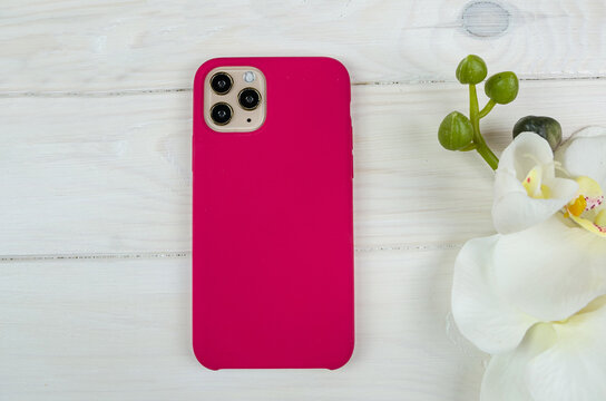 Purple Case For A Smartphone On A White Wooden Background. View From Above.