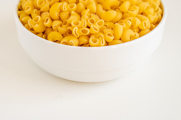 Raw dry uncooked Mini pipe rigate pasta spaghetti noodle on white bowl wooden background for basil tomato pesto sauce Homemade Italian food organic whole wheat vegan spaghetti for a healthy meal