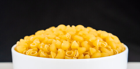 Raw dry uncooked Mini pipe rigate pasta spaghetti noodle on white bowl wooden background for basil tomato pesto sauce Homemade Italian food organic whole wheat vegan spaghetti for a healthy meal