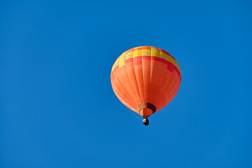 Hot-air ballon. Orange balloon in front of a shining blue sky.