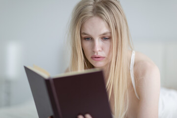 Young woman reading a book in bed.