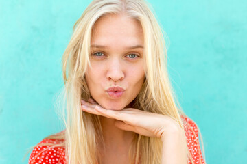 Portrait of beautiful young blonde woman posing and giving a kiss to the camera.
