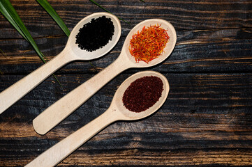 Spices. in wooden spoons. On a wooden burnt background in the village style, saffron, black cumin, sumac and other spices are highlighted. Culinary background with the ability to to insert a small pie