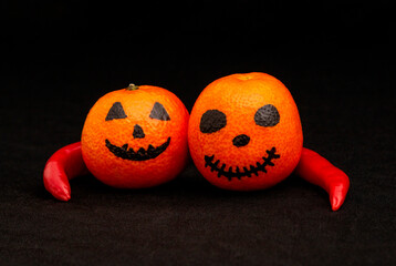 orange mandarines painted like a halloween pumpkin, happy halloween citrus, red pepper