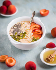 Apricot smoothie in a bowl with honey, chia, sunflower seeds and apricots.