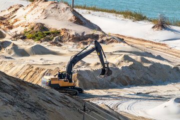 Sand extraction with machinery excavator at quartz quarry close-up. Sand dunes hills terrain...