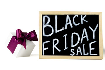 Fototapeta na wymiar White gift box with lilac ribbon next to Black Friday Sale sign on white background