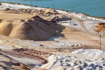 Sand extraction with machinery excavator at quartz quarry. Sand dunes hills terrain digging near...