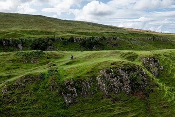 Fototapeta na wymiar The landscape near the Faerie Castle (Castle Ewen) at the Fairy Glen in Isle of Skye in Scotland with hiking tourists