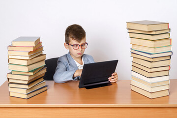 The student does homework using a tablet. He has books on both sides.