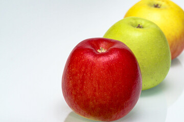 Three juicy ripe apples on a white background, close-up view.