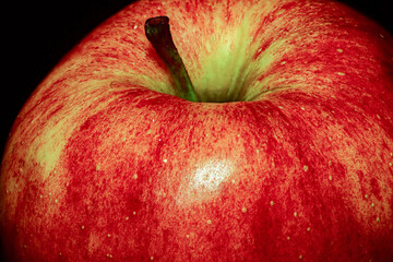 Red ripe apple in raindrops on a dark background.