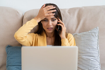 Confused woman doing facepalm gesture, touching head with palm, looking at screen while working on...