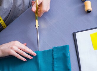 Woman tailor working on a clothing sewing stitching measuring fa