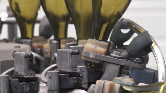 Wine bottling factory, green wine bottles are sanitized in industrial