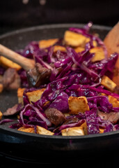 Preparing a vegan Asian Pad Thai stir fry with red cabbage, tofu and noodles. 
