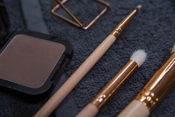 Various cosmetic products on a dark background.Makeup brushes, face shadows in different colors, scissors and chips.
