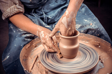 Fototapeta na wymiar Young female potter working on a potter's wheel