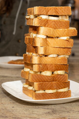 A stack of peanut butter and banana sandwiches on a white plate sitting on top of a kitchen counter.